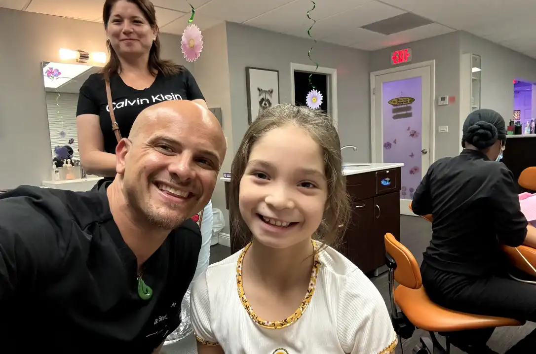 Dentist posing with child and parent for picture